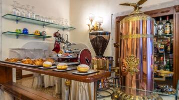 Un mostrador de panadería con pasteles, una máquina de café y una urna decorativa de cobre.