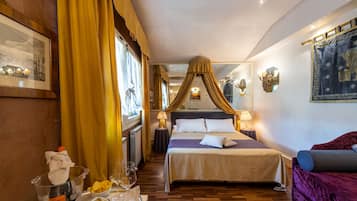 A hotel room with a four-poster bed, a sitting area with a purple sofa, a dining table with a glass of wine, and a bowl of olives.