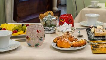 Taula de l'esmorzar amb pastissos, fruita i una tassa de cafè.