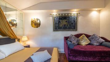 Une chambre d’hôtel avec un lit, un canapé, une lampe fixée au mur et un tableau encadré.