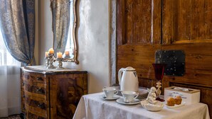 Una habitación con un aparador de madera, una mesa con servicio de té, un espejo y una puerta de madera.