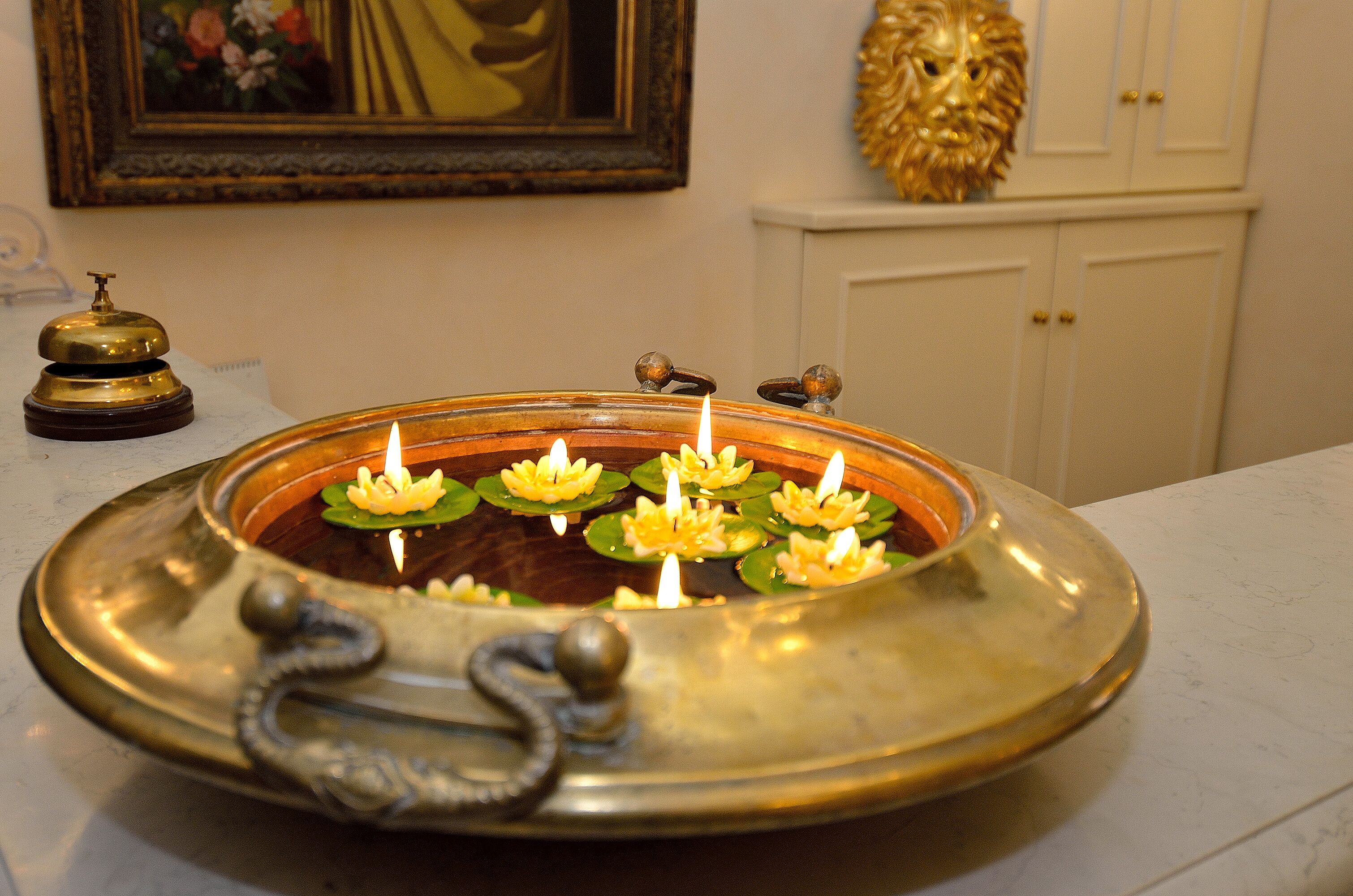 Una bandeja de bronce con flores de loto y velas.
