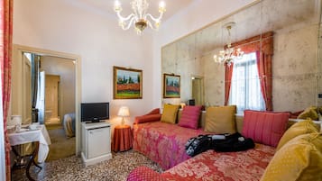 A hotel room with a bed, a television, a desk with a lamp, and a large mirror.