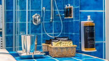 A bathroom with blue tiles, a hand soap dispenser, and a wicker basket with toiletries.