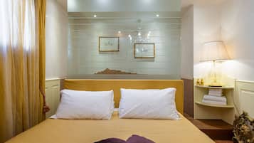 A hotel room with a bed, a nightstand with a lamp, and a mirror above the bed.