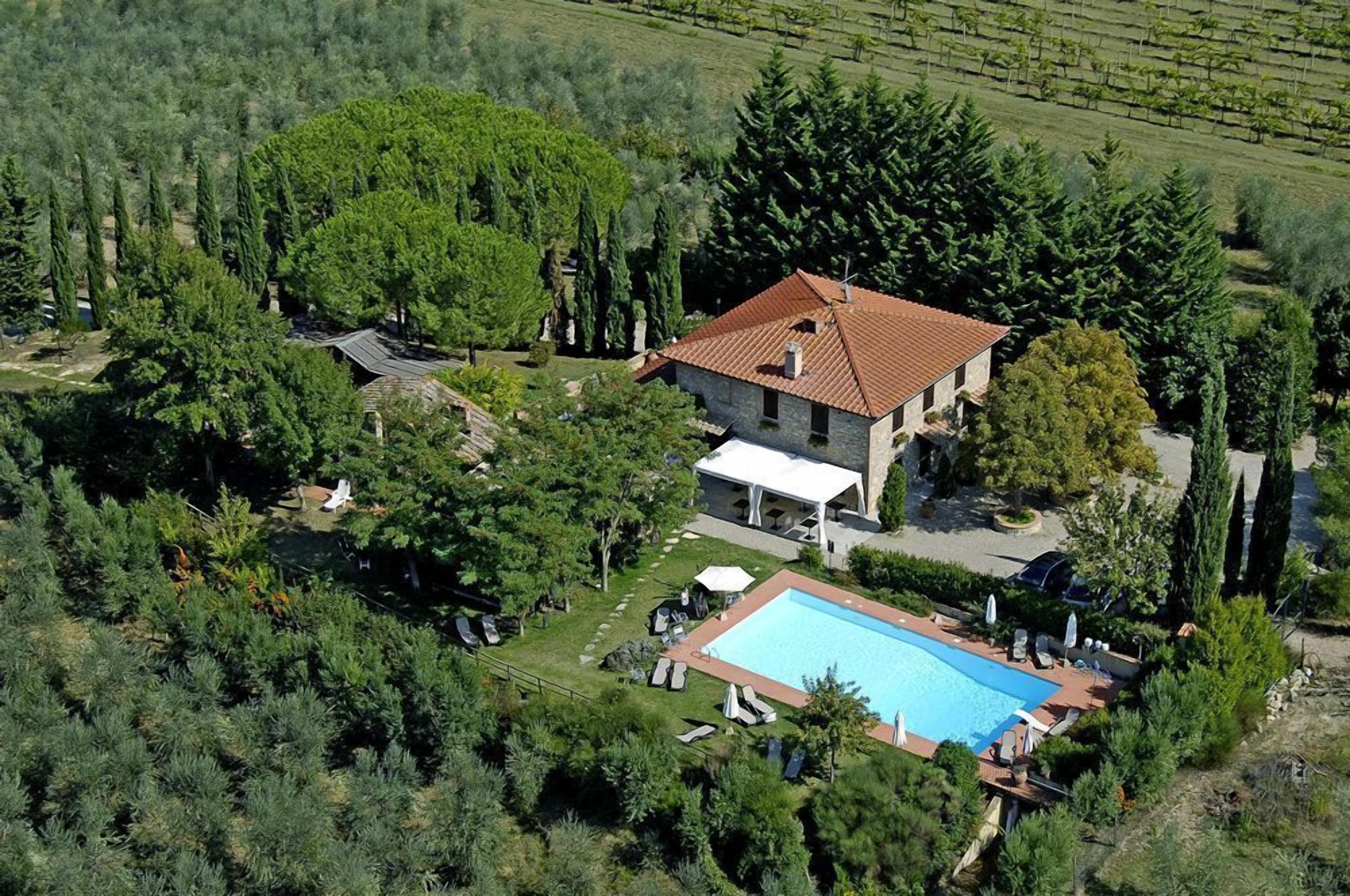 Luftaufnahme eines Hauses mit Schwimmbecken, umgeben von üppiger Vegetation und Bäumen.