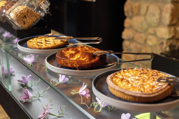A dessert display with three cakes on plates, each with a serving utensil.