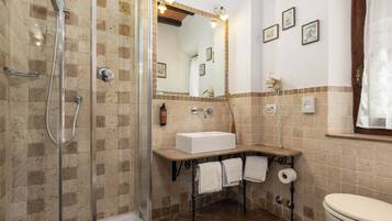 Een badkamer met douche, wastafel, toilet en spiegel.