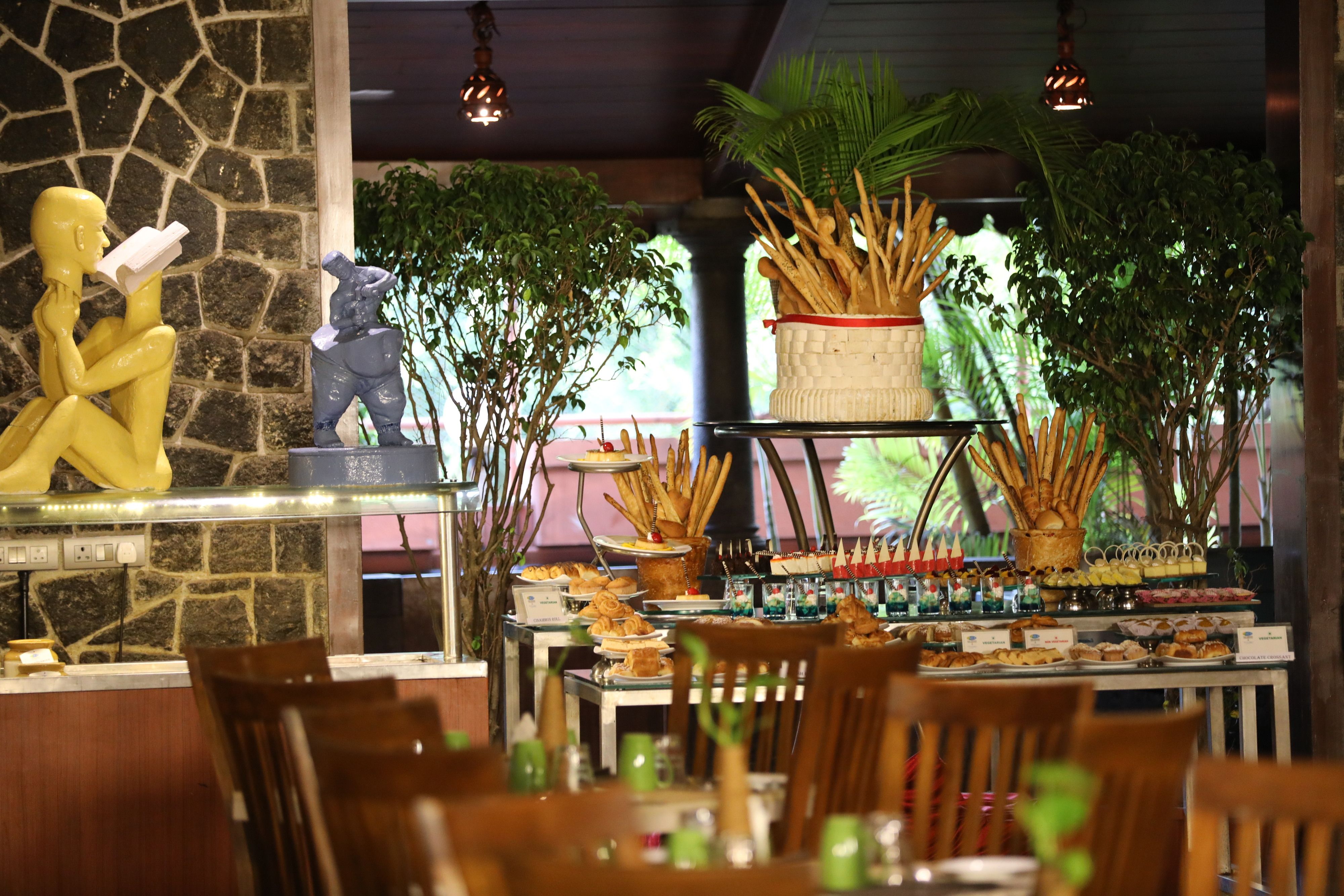 A restaurant with a stone wall, wooden chairs, and a buffet with various food items.