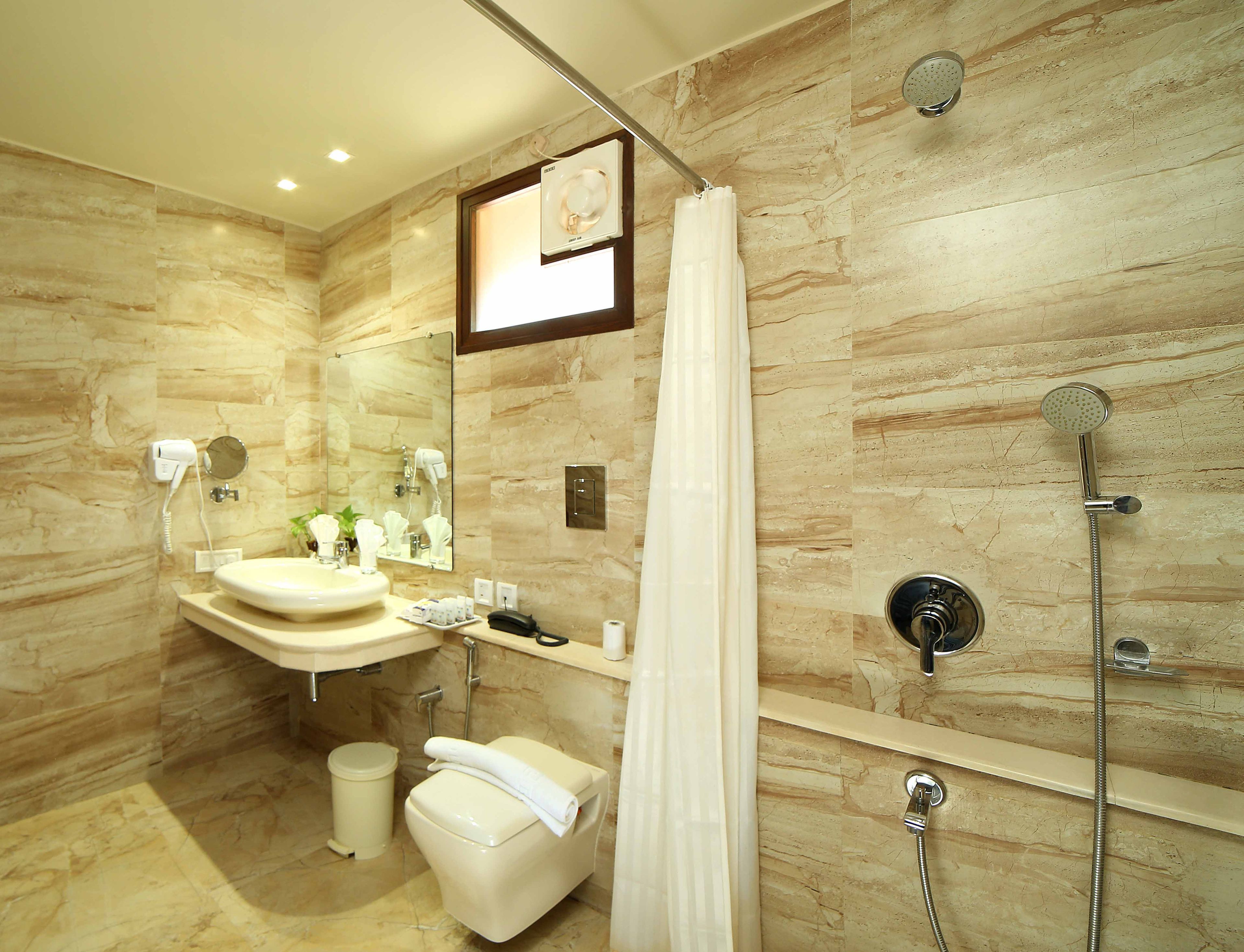 A modern bathroom with a marble wall, a sink, a toilet, a shower, and a mirror.