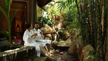 Guests can relax in a serene garden setting with a small water feature, featuring a waterfall and pond with lotus flowers.