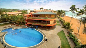 Un hotel con piscina, vista al mar y un edificio de varios pisos con balcones.