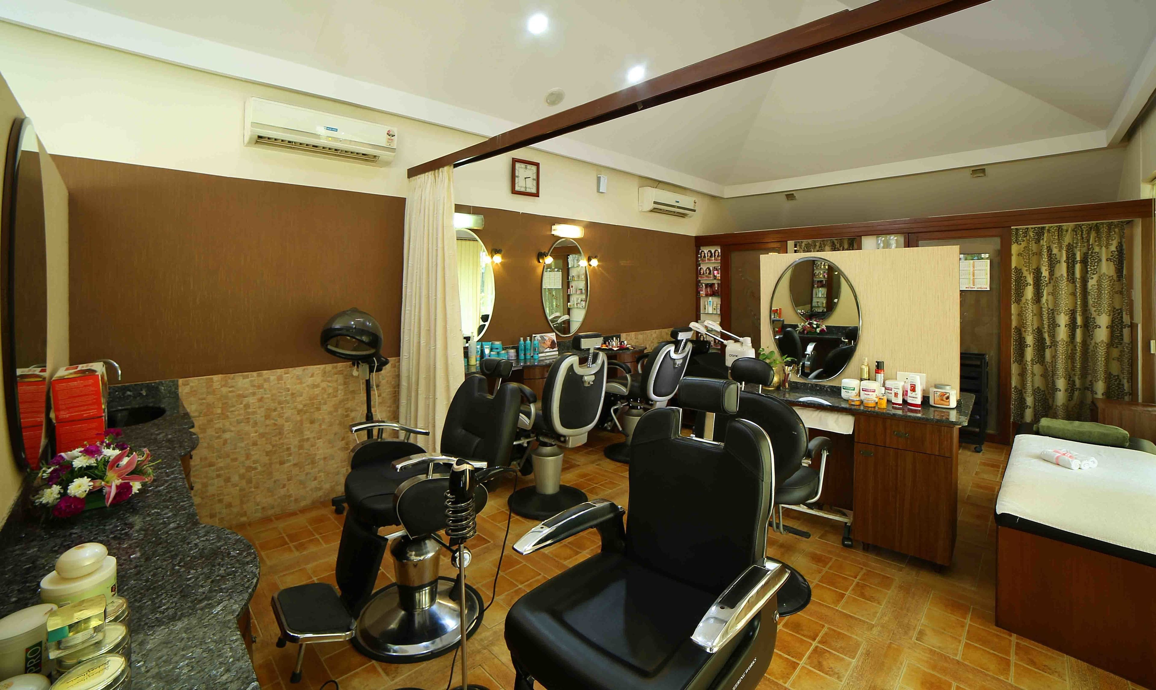 Un salón de belleza con varias sillas de peluquería, un espejo y una barra con diversos productos capilares.