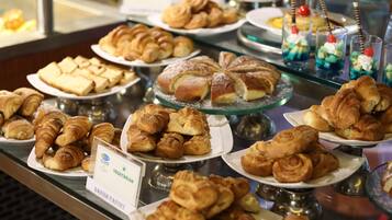 A variety of pastries and desserts displayed on multiple plates and stands.