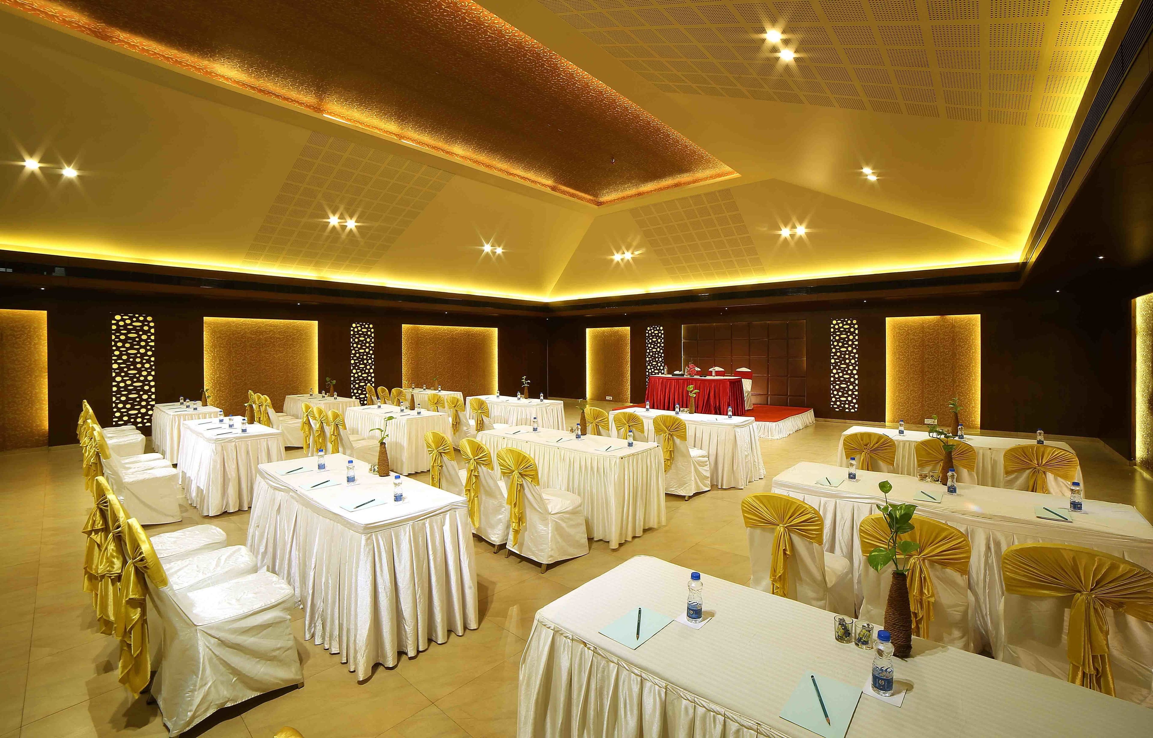 A banquet hall with round tables, white tablecloths, and yellow sashes.