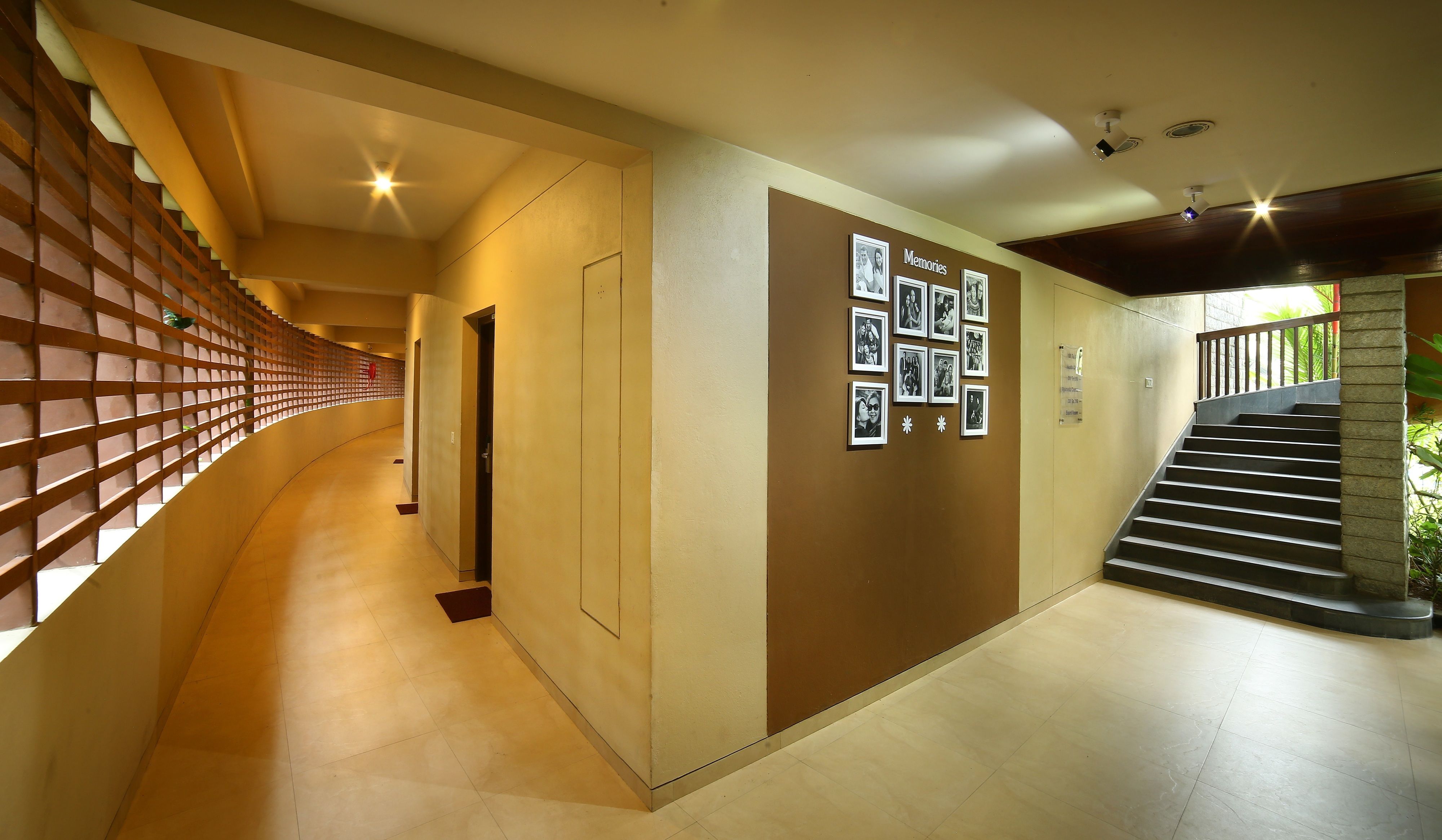 Een hal met een wand van houten latten, een trap en een wand met ingelijste foto’s met de tekst “Memories”.