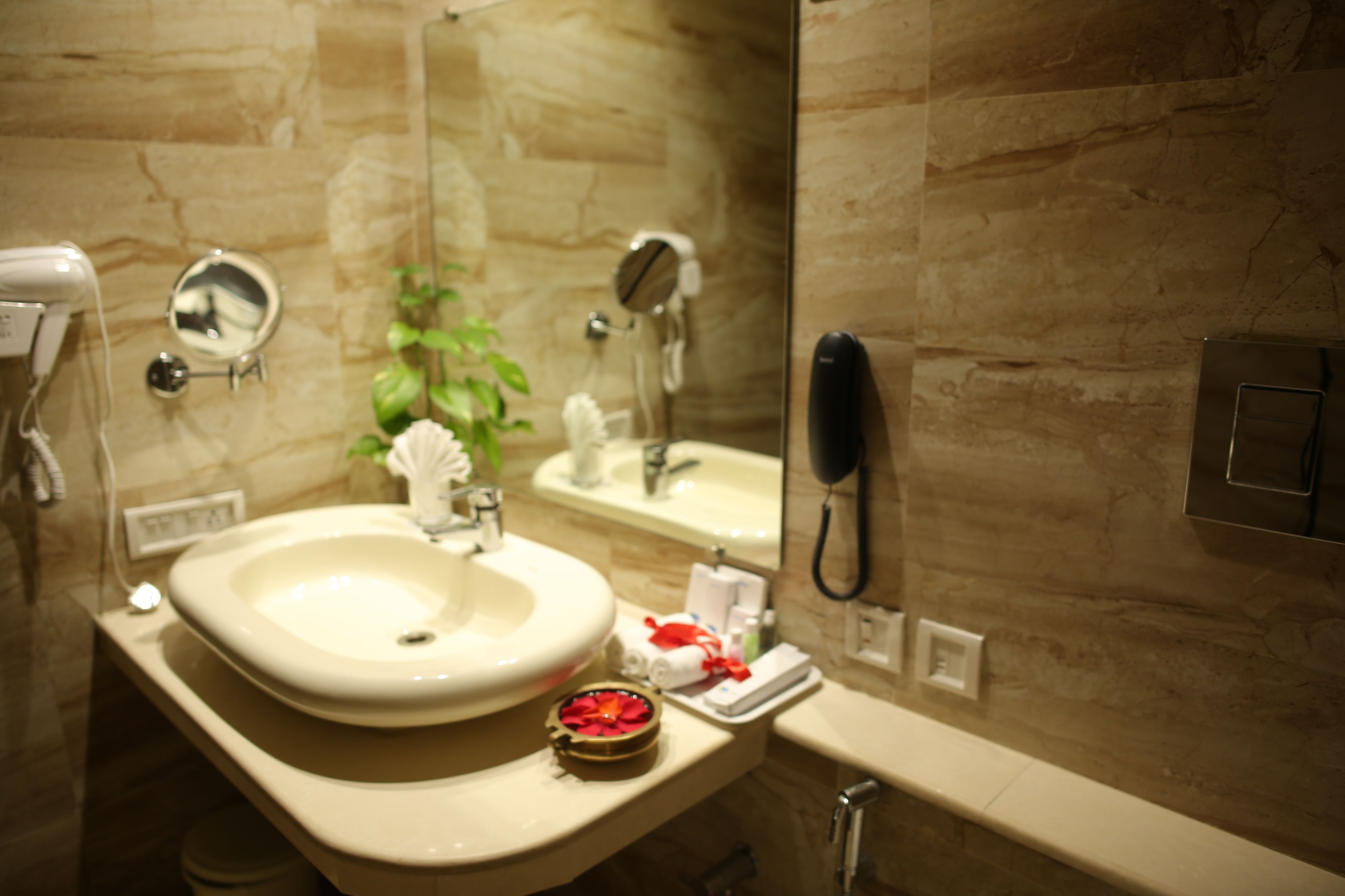 Une salle de bain équipée d’un lavabo, d’un miroir, d’un sèche-cheveux et d’un téléphone.