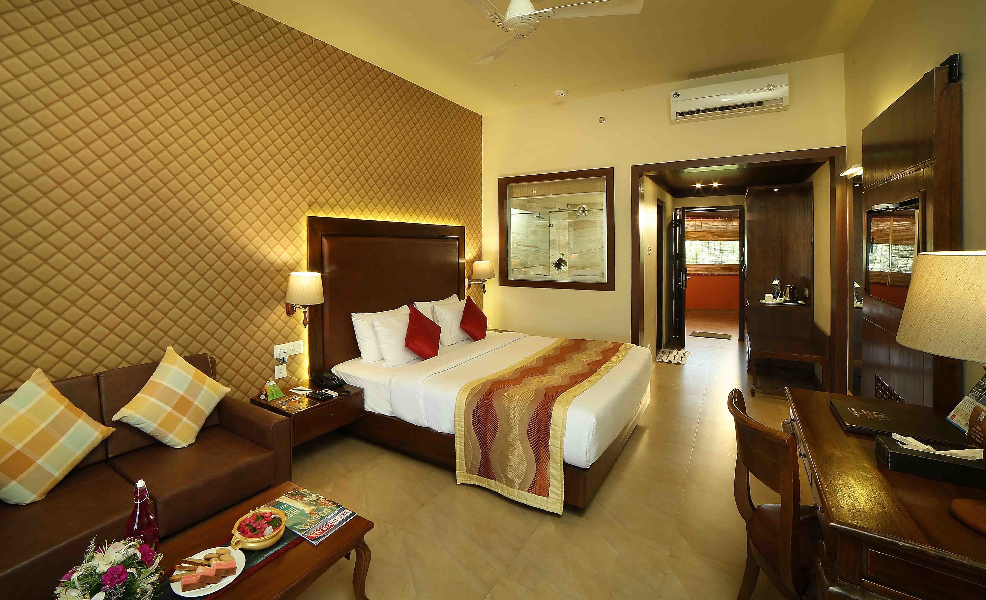 A hotel room with a bed, a sofa, a desk, and a mirror.