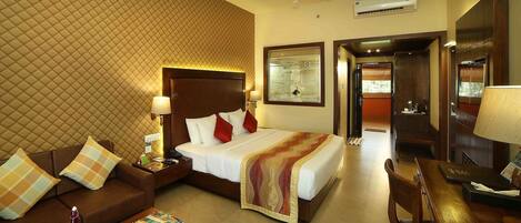 A hotel room with a bed, a sofa, a desk, and a mirror.