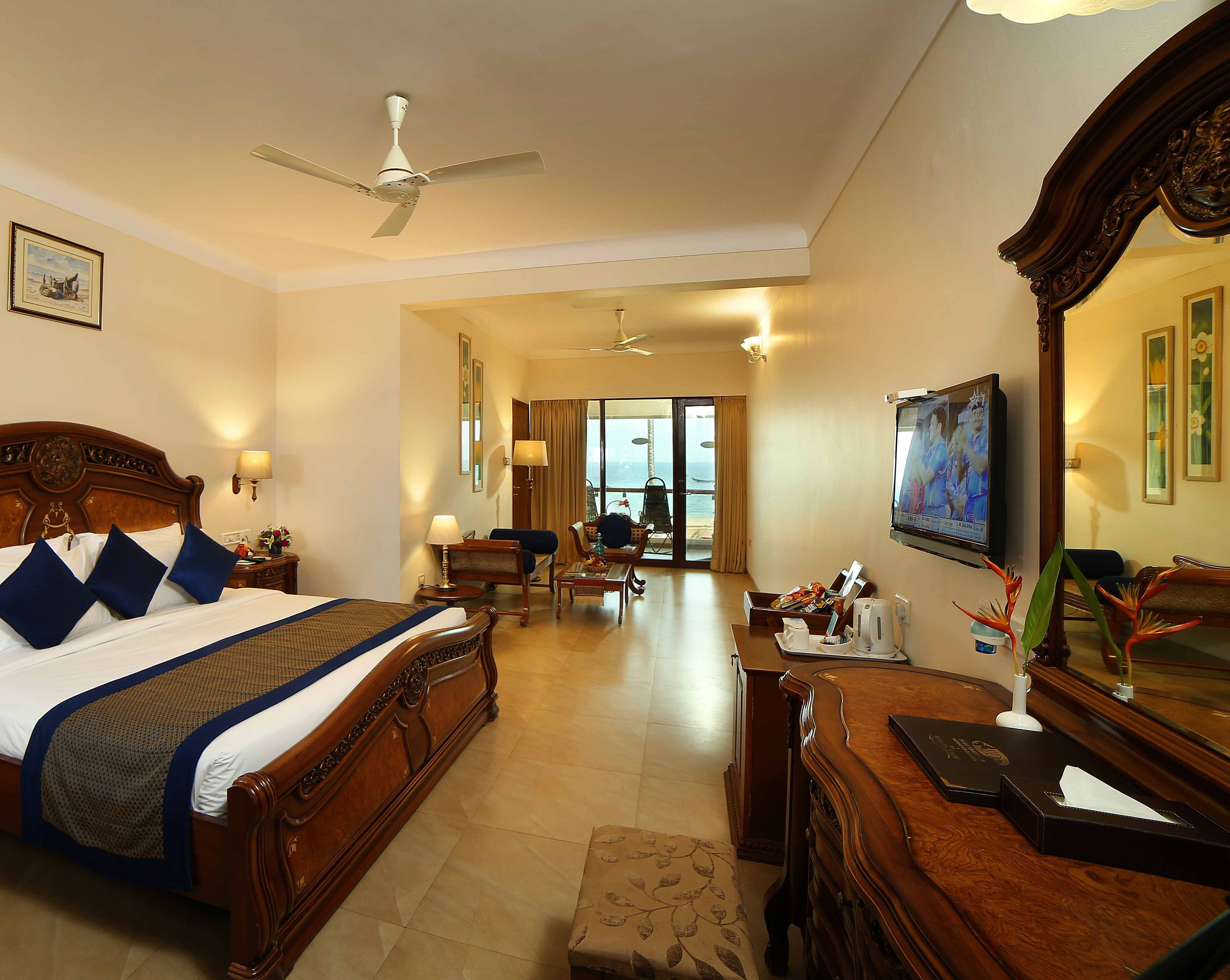 Habitación de hotel con una cama grande, un escritorio, una televisión y vista a la playa.