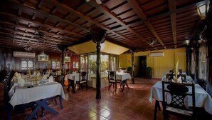 A restaurant with wooden beams, tiled floors, and tables set for dining. - Paradise Resorts (Kottayam)