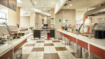 A modern hotel lobby with a check-in counter, a seating area, and a reception desk.