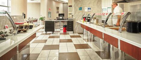 A modern hotel lobby with a check-in counter, a seating area, and a reception desk.