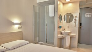 A hotel room with a bed, a shower, a sink, and a mirror. - Hello Hotels Bucharest (Bucharest)
