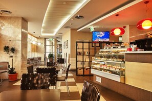 A modern hotel lobby with a dining area, a buffet, and a TV screen. - Hello Hotels Bucharest (Bucharest)