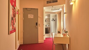 A hotel hallway with a red carpet, a white reception desk, a mirror, and a coat rack. - Hello Hotels Bucharest (Bucharest)