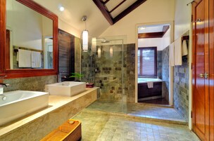 A modern bathroom with two sinks, a glass shower enclosure, and a wooden door.