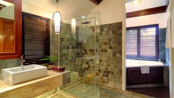 A modern bathroom with a glass-enclosed shower, a large sink, and a bathtub.