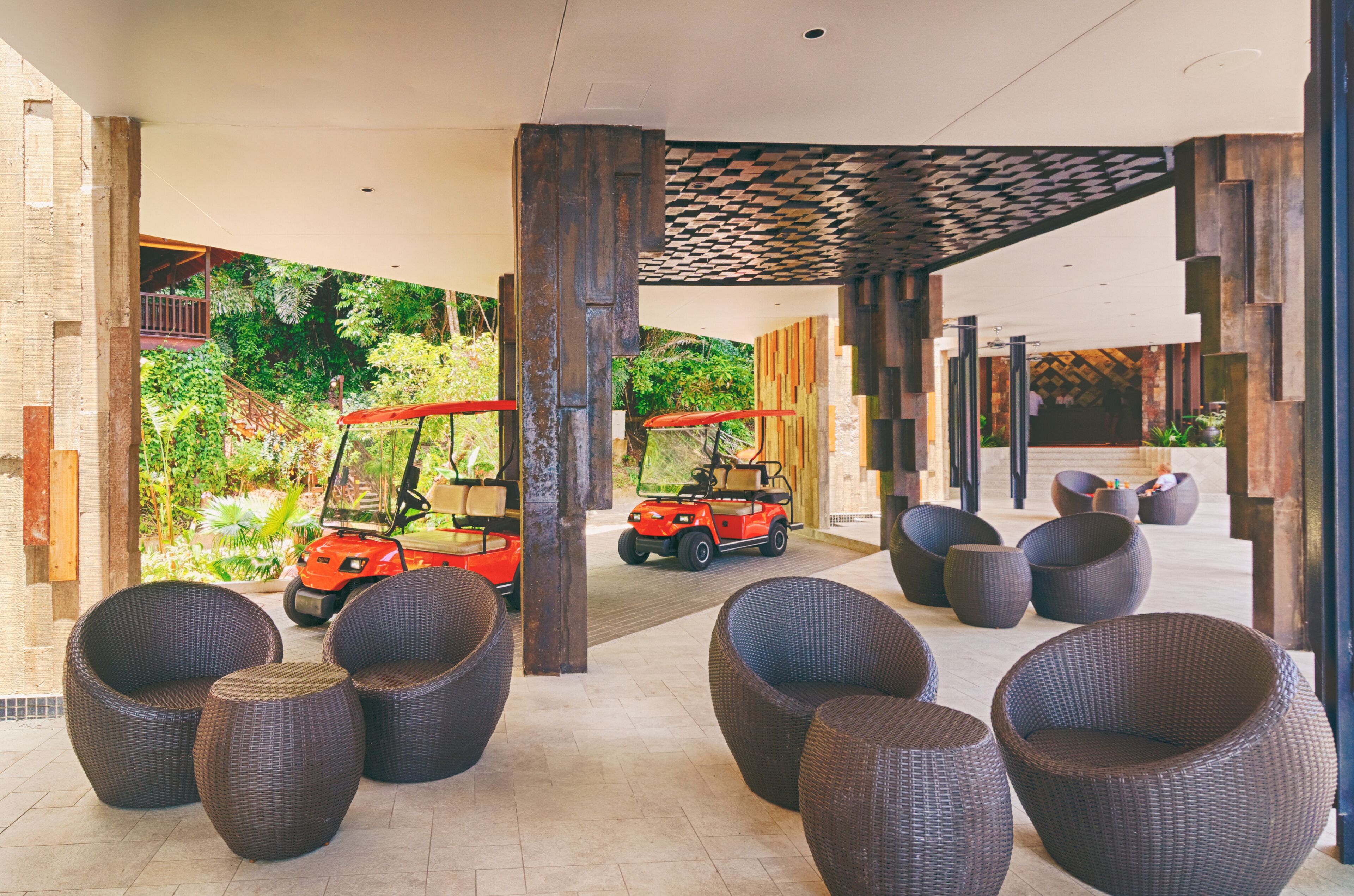 A covered outdoor seating area with wicker chairs and two golf carts.
