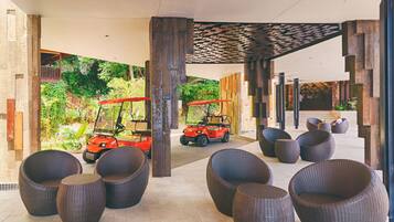 A covered outdoor seating area with wicker chairs and two golf carts.