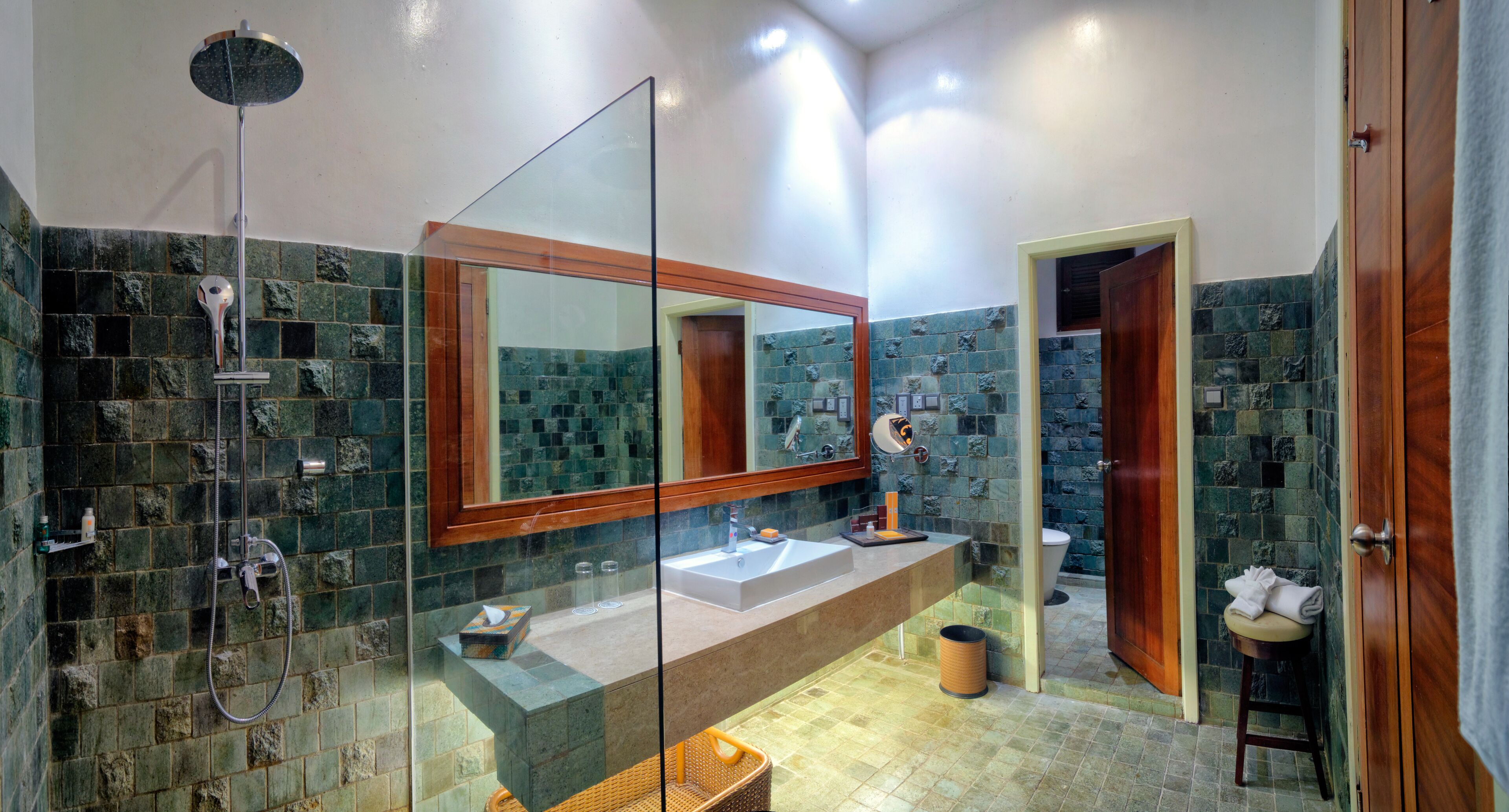 A modern bathroom with a glass-enclosed shower, a large mirror, a sink, and a toilet.