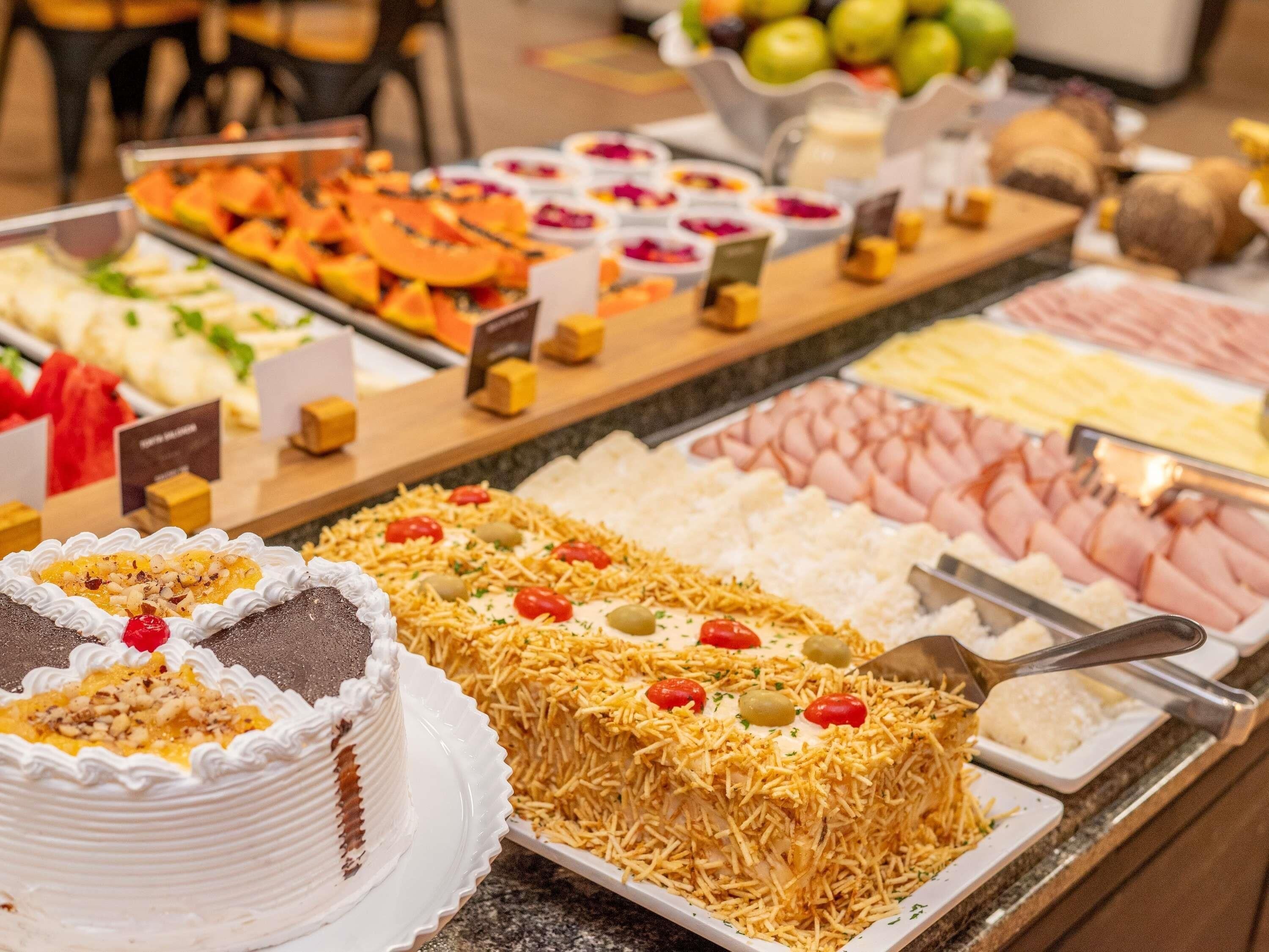 Un bufé con diversas opciones de comida, incluyendo pasteles, frutas y carnes.