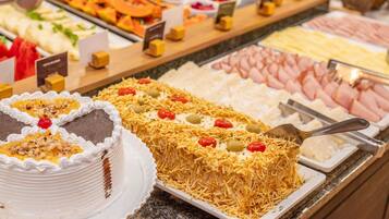 Un bufé con diversas opciones de comida, incluyendo pasteles, frutas y carnes.