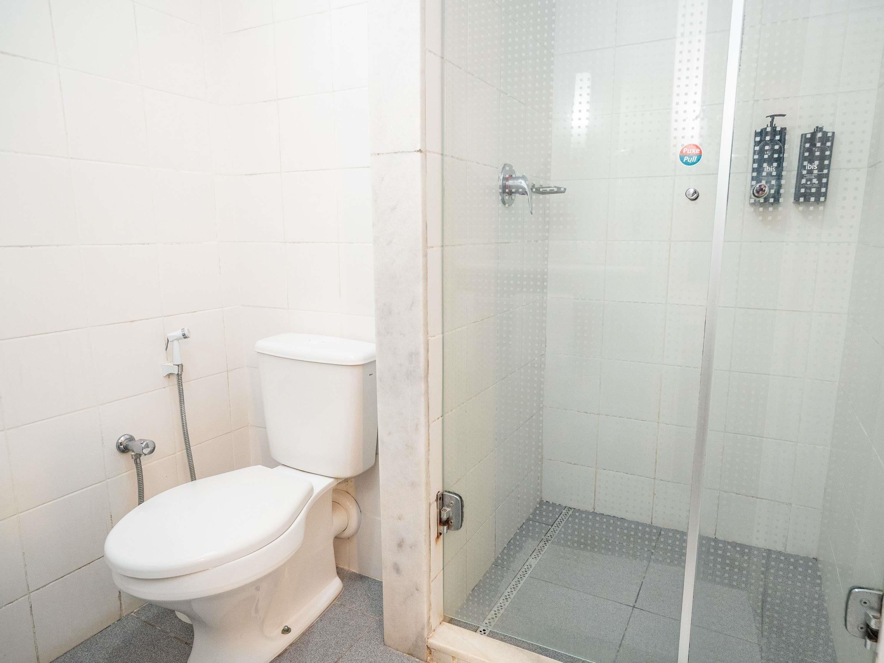 A bathroom with a toilet, a shower with a glass door, and a tiled floor.