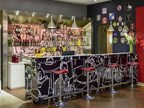 A bar area with stools, a counter with bottles, and wall decorations. - Ibis Belem Aeroporto (Belém)
