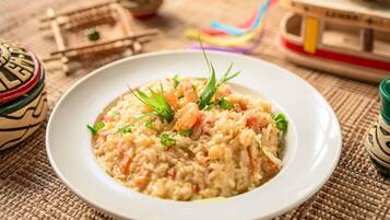 Un plato de arroz con verduras y hierbas, sobre un tapete tejido.