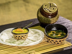 A table with two bowls of food, a decorative vase, and a woven mat. - Ibis Belem Aeroporto (Belém)