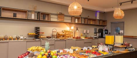 A buffet with various fruits, pastries, and beverages.