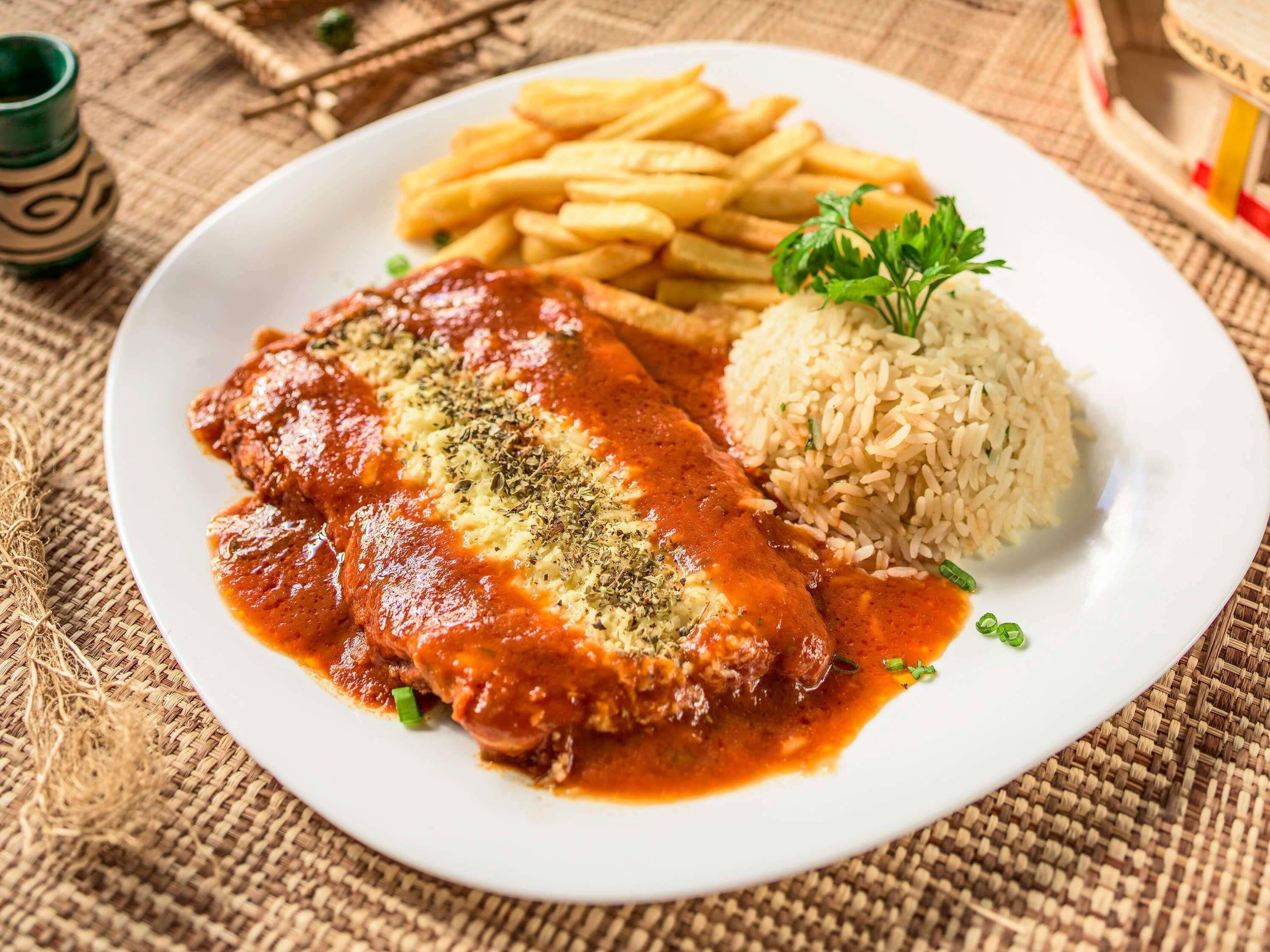 A plate with a meat dish, rice, and fries.