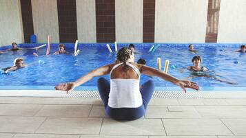 Swimmers enjoy laps in the hotel's indoor pool, surrounded by a patterned tile floor and walls.
