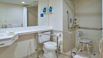 A bathroom with a toilet, a shower, a grab bar, and a wheelchair-accessible chair.