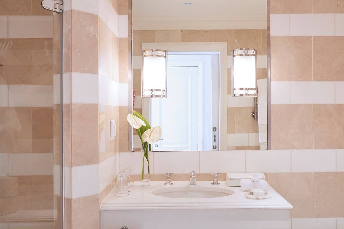 A bathroom with a glass shower enclosure, a white sink, and a large mirror.