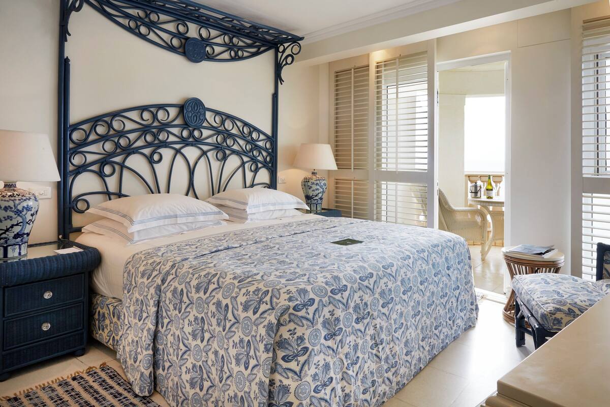 A bedroom with a large bed, a nightstand, a chair, and a small table.