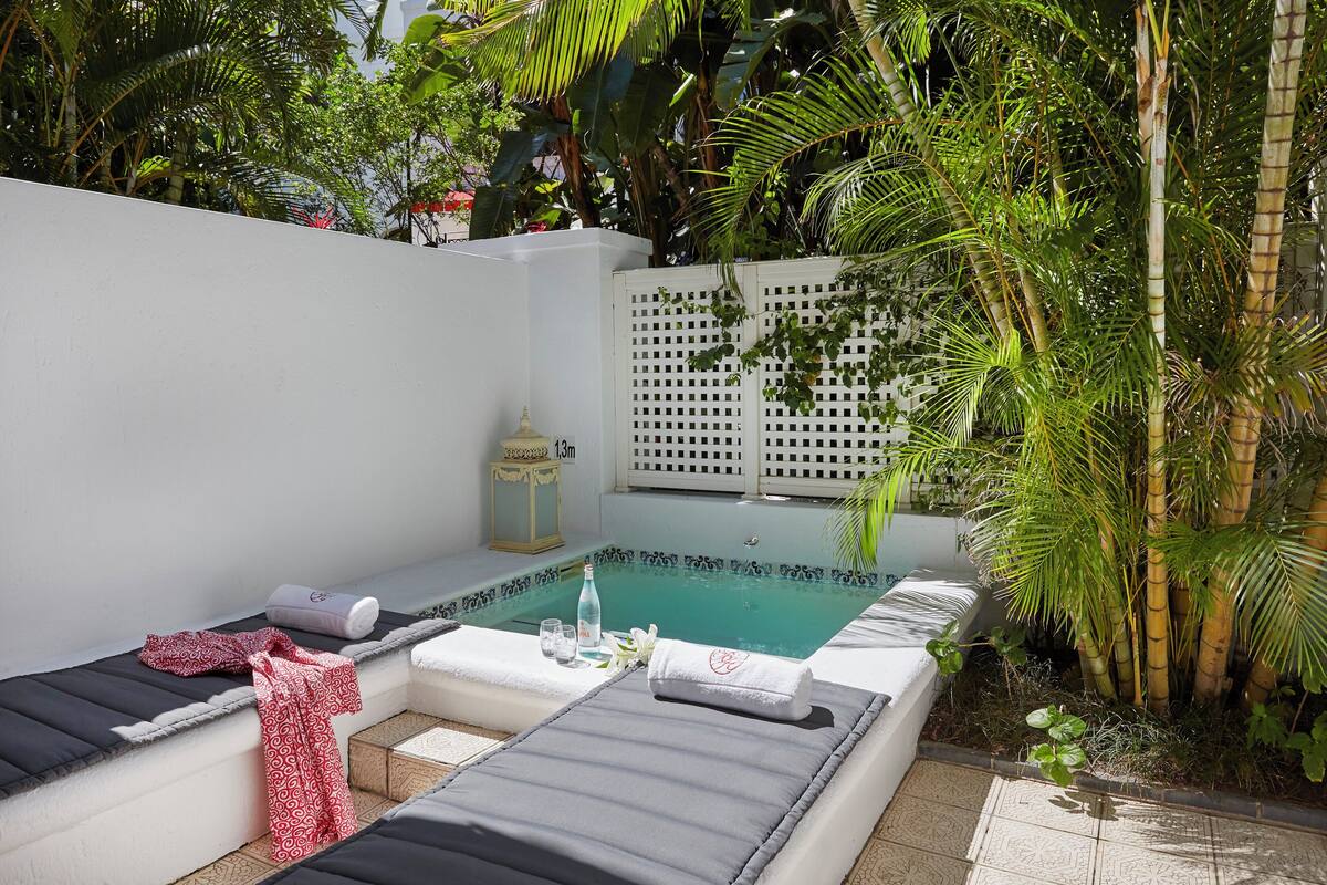 A spa area with a pool, lounge chairs, and a white wall.