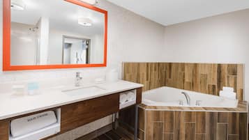 A modern bathroom with a large mirror, a wooden vanity, a bathtub, and a hair dryer.