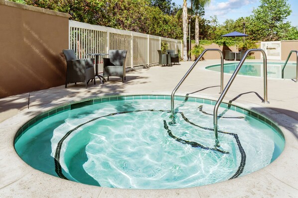 A swimming pool with a tiled edge, surrounded by a fence and outdoor seating. - Hampton Inn & Suites Thousand Oaks, CA (Thousand Oaks)